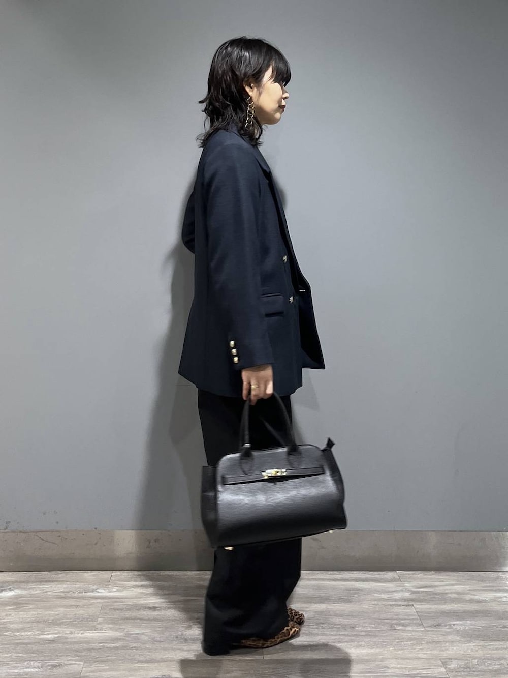 ブルー系のテーラードジャケット、ブラック系のショルダーバッグ、グレー系のニット/セーターを着用したレディースの春コーディネートの2枚目の写真