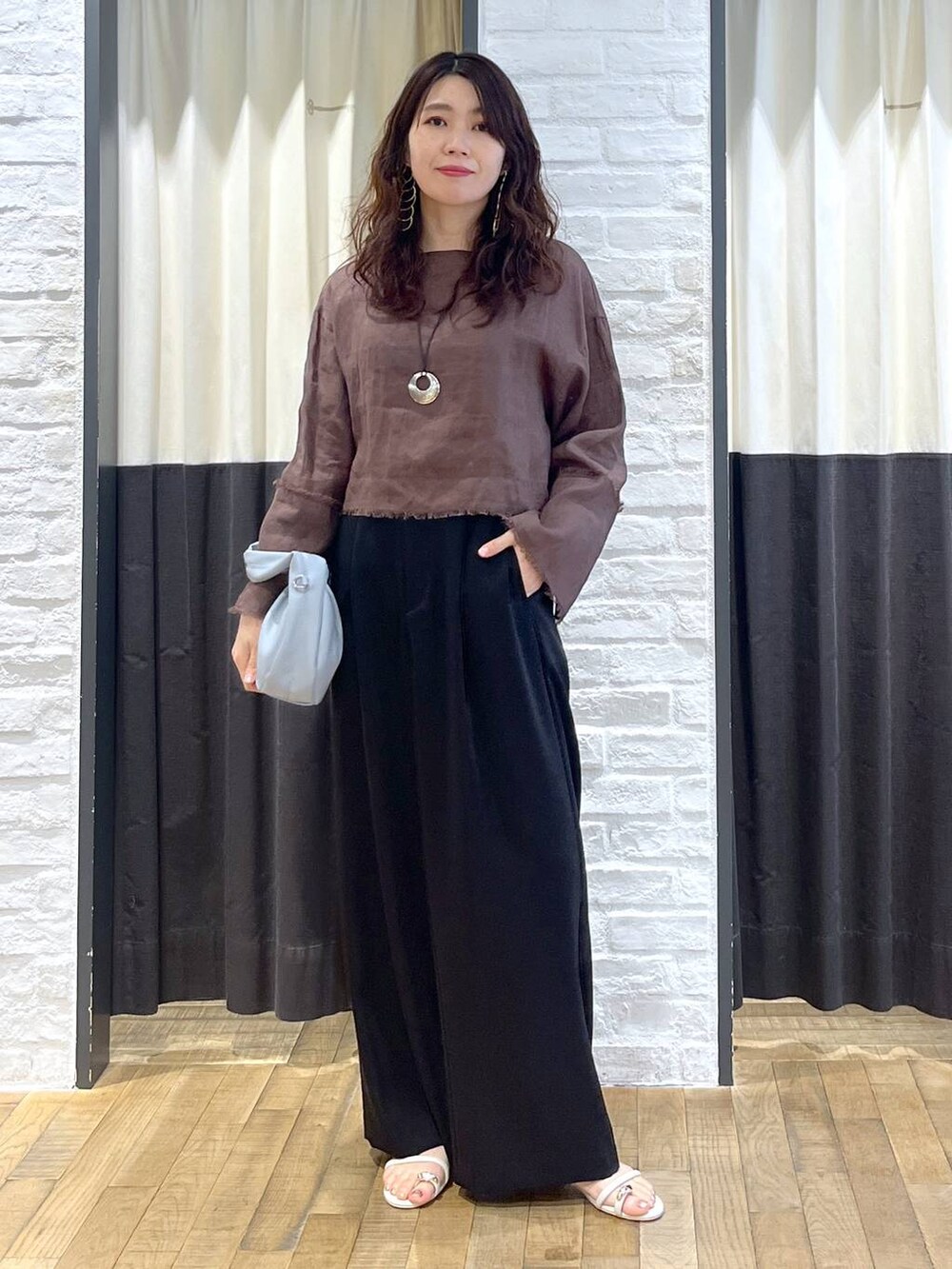 ブルー系のハンドバッグ、ブラウン系のシャツ/ブラウス、ホワイト系のサンダルを着用したレディースの秋コーディネートの5枚目の写真