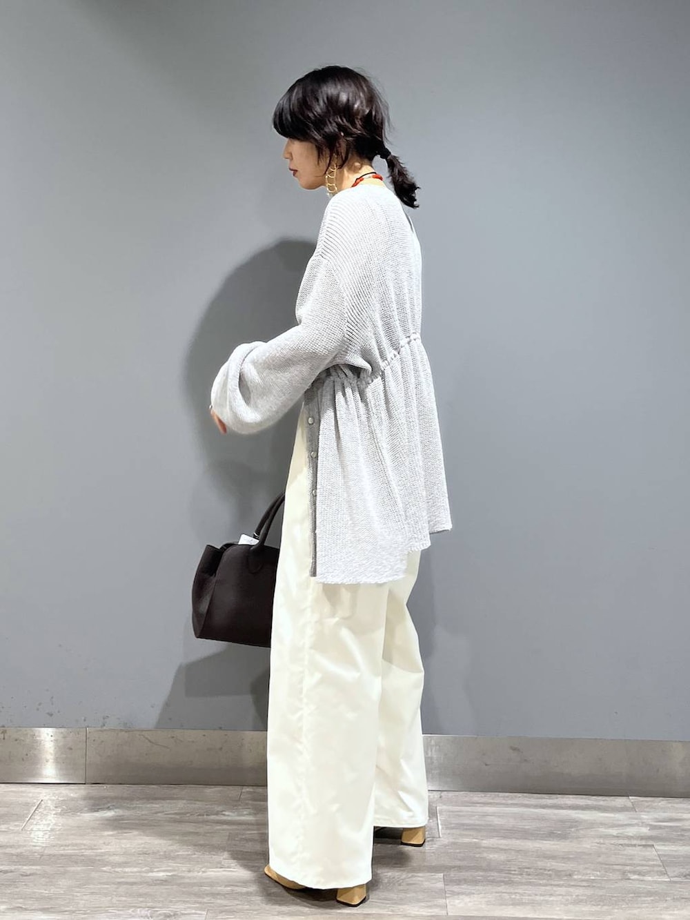 ブラウン系のショルダーバッグ、ホワイト系のスラックス、グレー系のカーディガン/ボレロを着用したレディースの春コーディネートの4枚目の写真