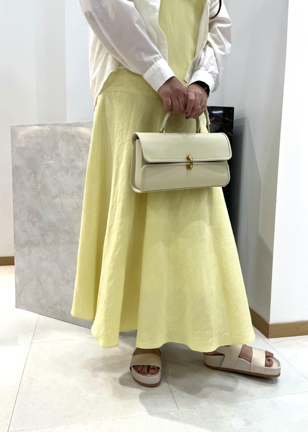 ベージュ系のショルダーバッグ、ホワイト系のシャツ/ブラウス、ベージュ系のサンダルを着用したレディースの春コーディネートの6枚目の写真