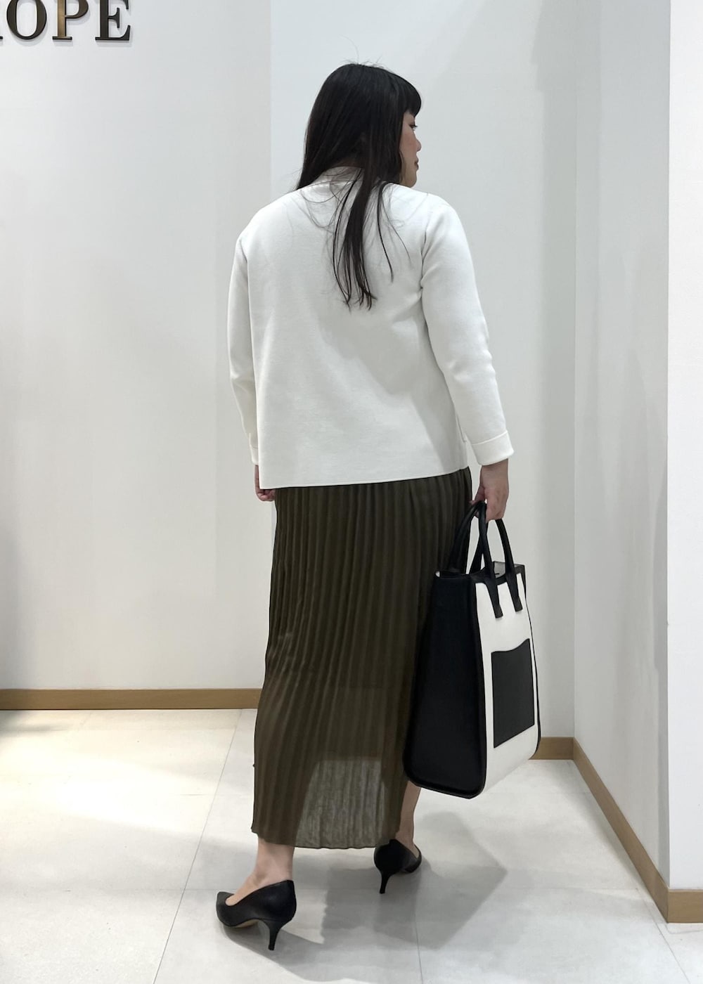 ブラック系のパンプス、ブラック系のトートバッグ、ホワイト系のテーラードジャケットを着用したレディースの春コーディネートの4枚目の写真