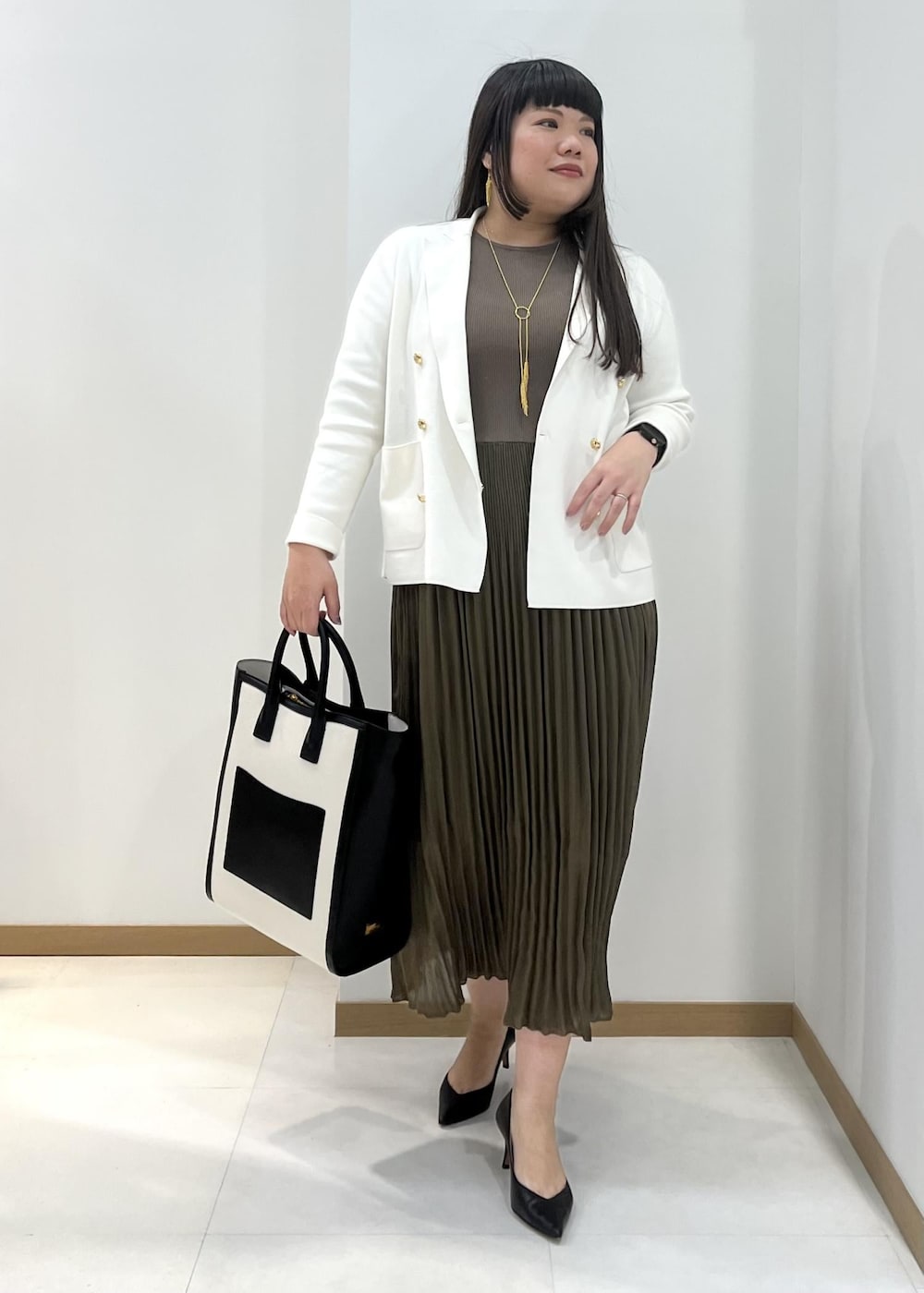 ブラック系のパンプス、ブラック系のトートバッグ、ホワイト系のテーラードジャケットを着用したレディースの春コーディネートの2枚目の写真