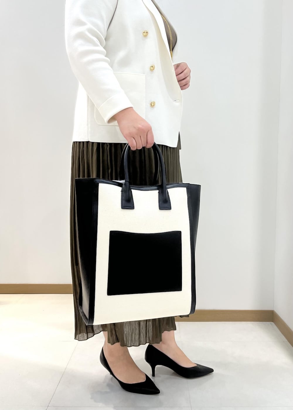 ブラック系のパンプス、ブラック系のトートバッグ、ホワイト系のテーラードジャケットを着用したレディースの春コーディネートの6枚目の写真