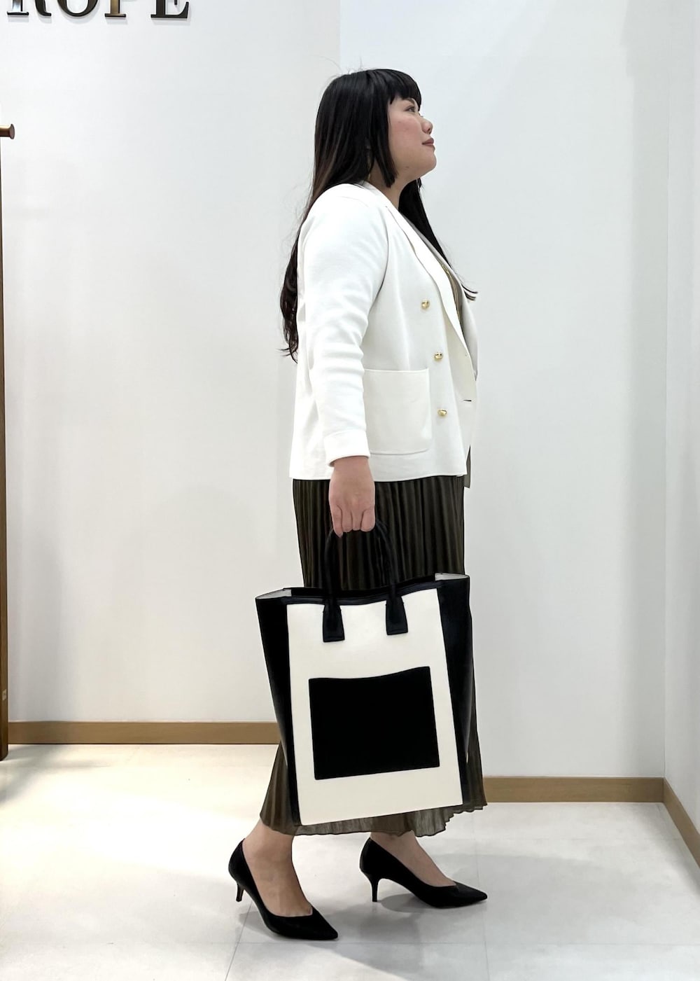 ブラック系のパンプス、ブラック系のトートバッグ、ホワイト系のテーラードジャケットを着用したレディースの春コーディネートの3枚目の写真