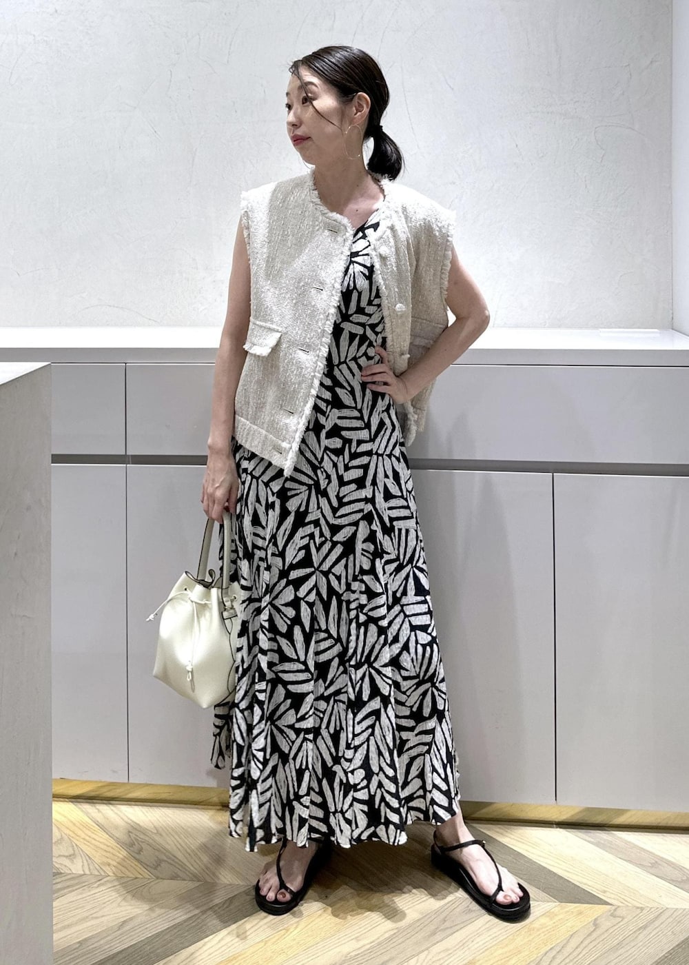 ホワイト系のショルダーバッグ、ブラック系のサンダル、ホワイト系のベストを着用したレディースの夏コーディネートの3枚目の写真