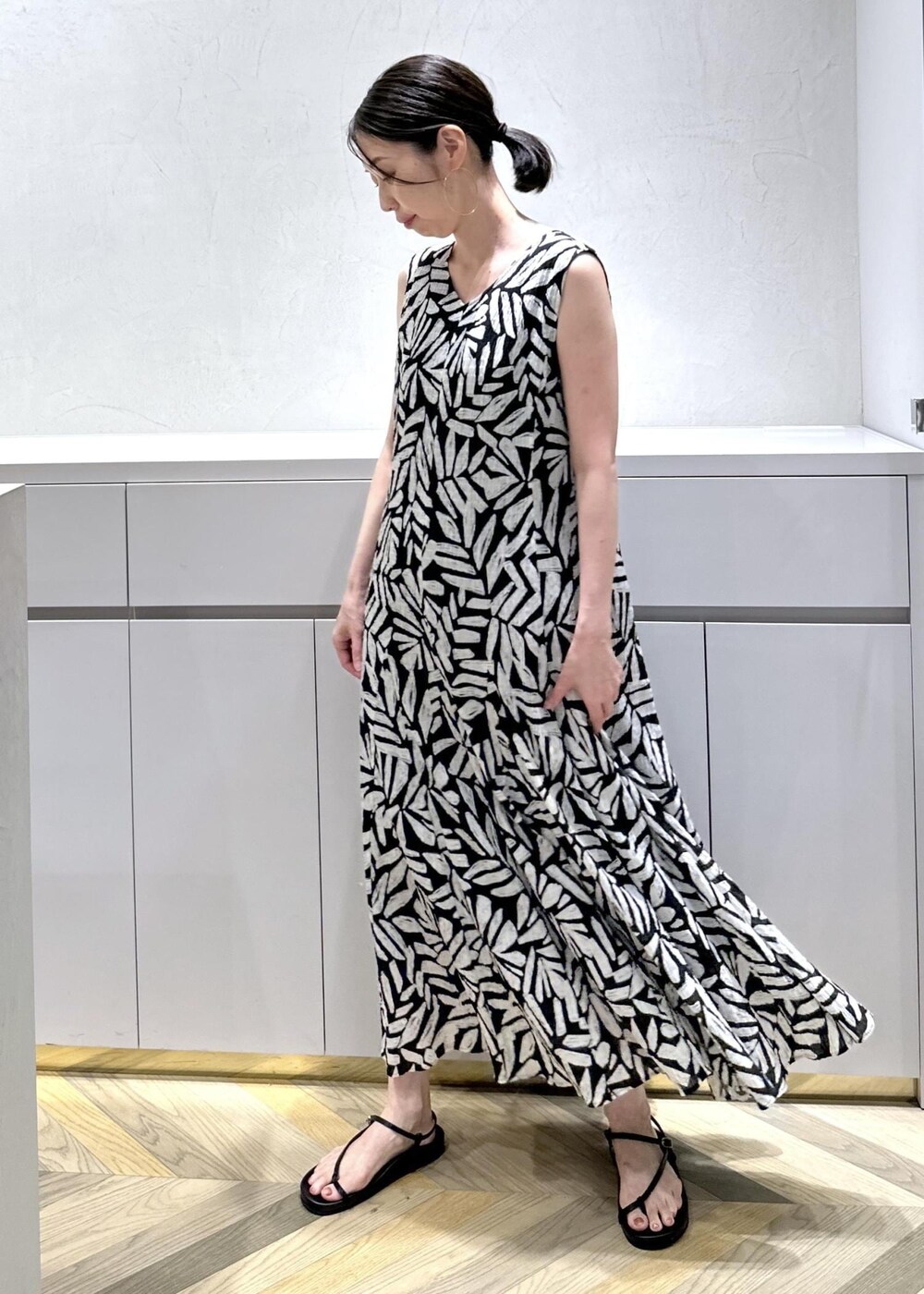 ホワイト系のショルダーバッグ、ブラック系のサンダル、ホワイト系のベストを着用したレディースの夏コーディネートの6枚目の写真