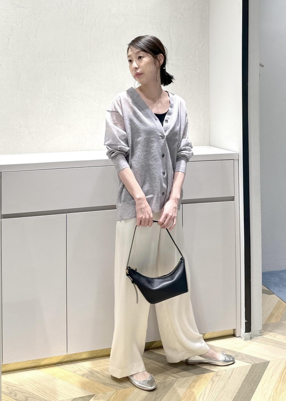 ブラック系のハンドバッグ、ホワイト系のその他パンツ、グレー系のカーディガン/ボレロを着用したレディースの春コーディネートの7枚目の写真