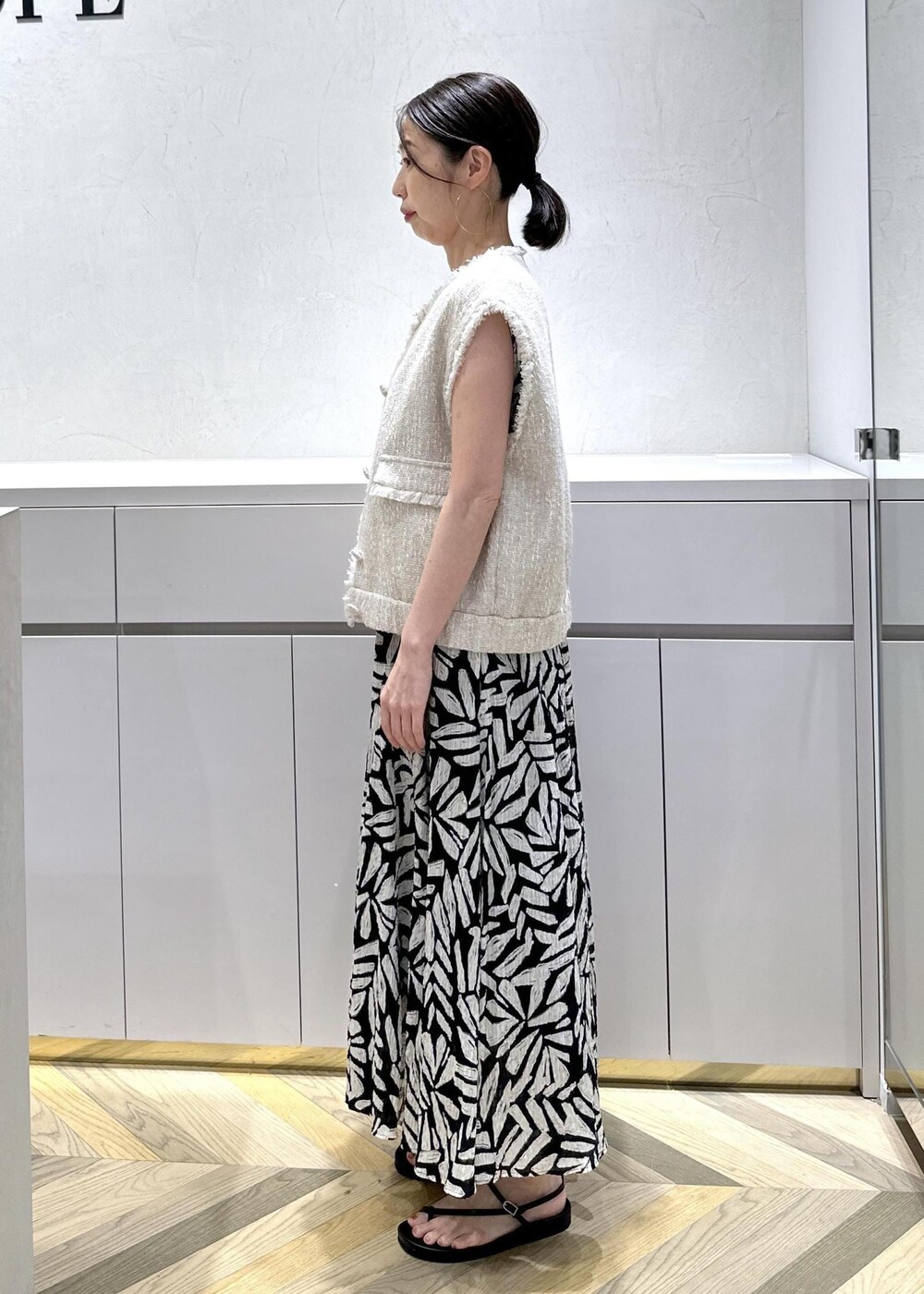 ホワイト系のショルダーバッグ、ブラック系のサンダル、ホワイト系のベストを着用したレディースの夏コーディネートの4枚目の写真