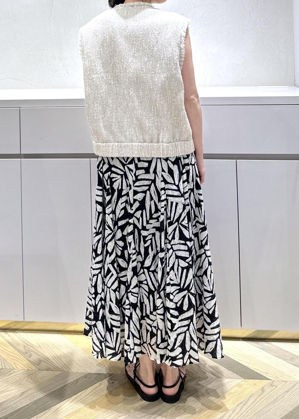 ホワイト系のショルダーバッグ、ブラック系のサンダル、ホワイト系のベストを着用したレディースの夏コーディネートの5枚目の写真