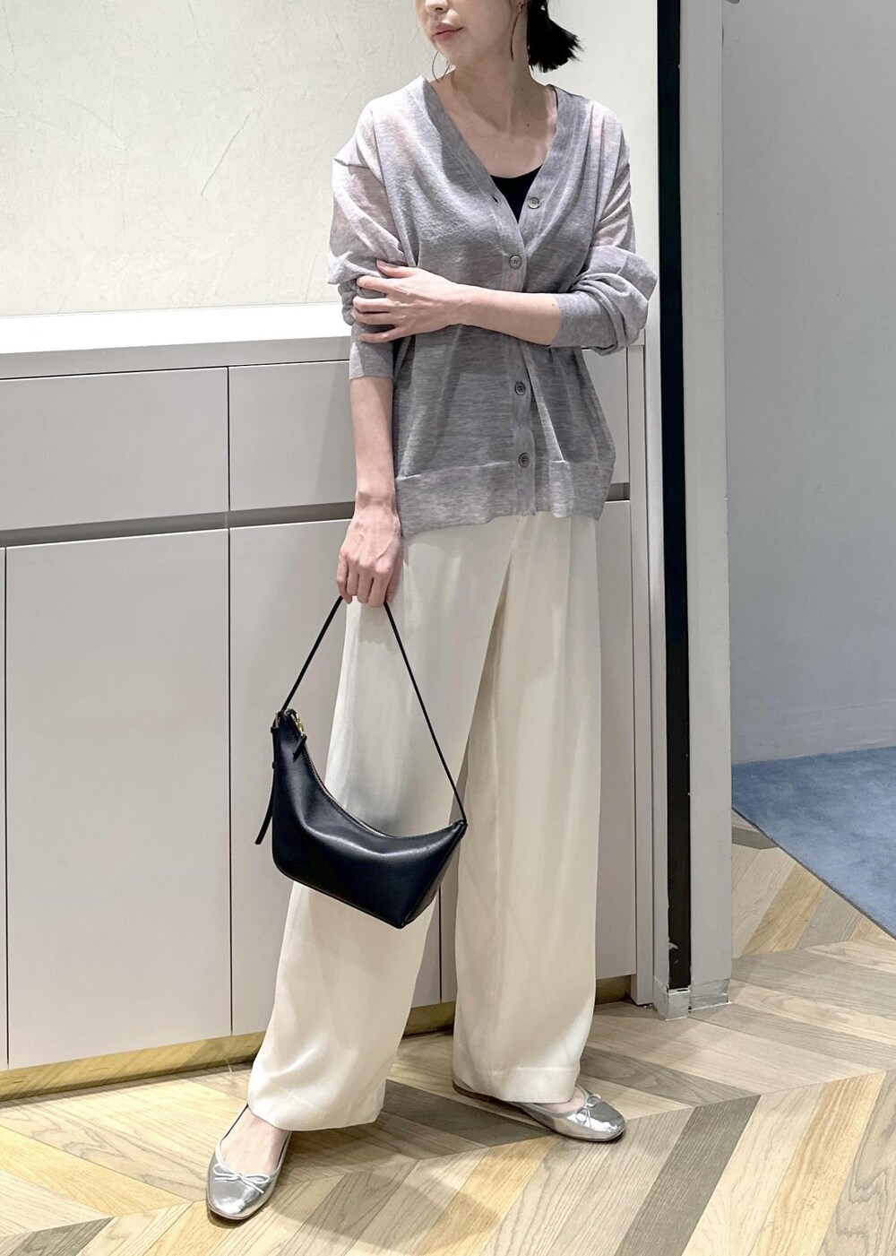 ブラック系のハンドバッグ、ホワイト系のその他パンツ、グレー系のカーディガン/ボレロを着用したレディースの春コーディネートの2枚目の写真