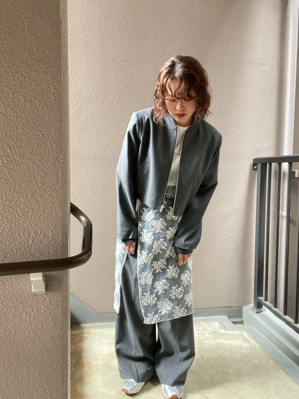 グレー系のノーカラージャケット、ホワイト系のスカート、グリーン系のサングラスを着用したレディースの春コーディネートの2枚目の写真