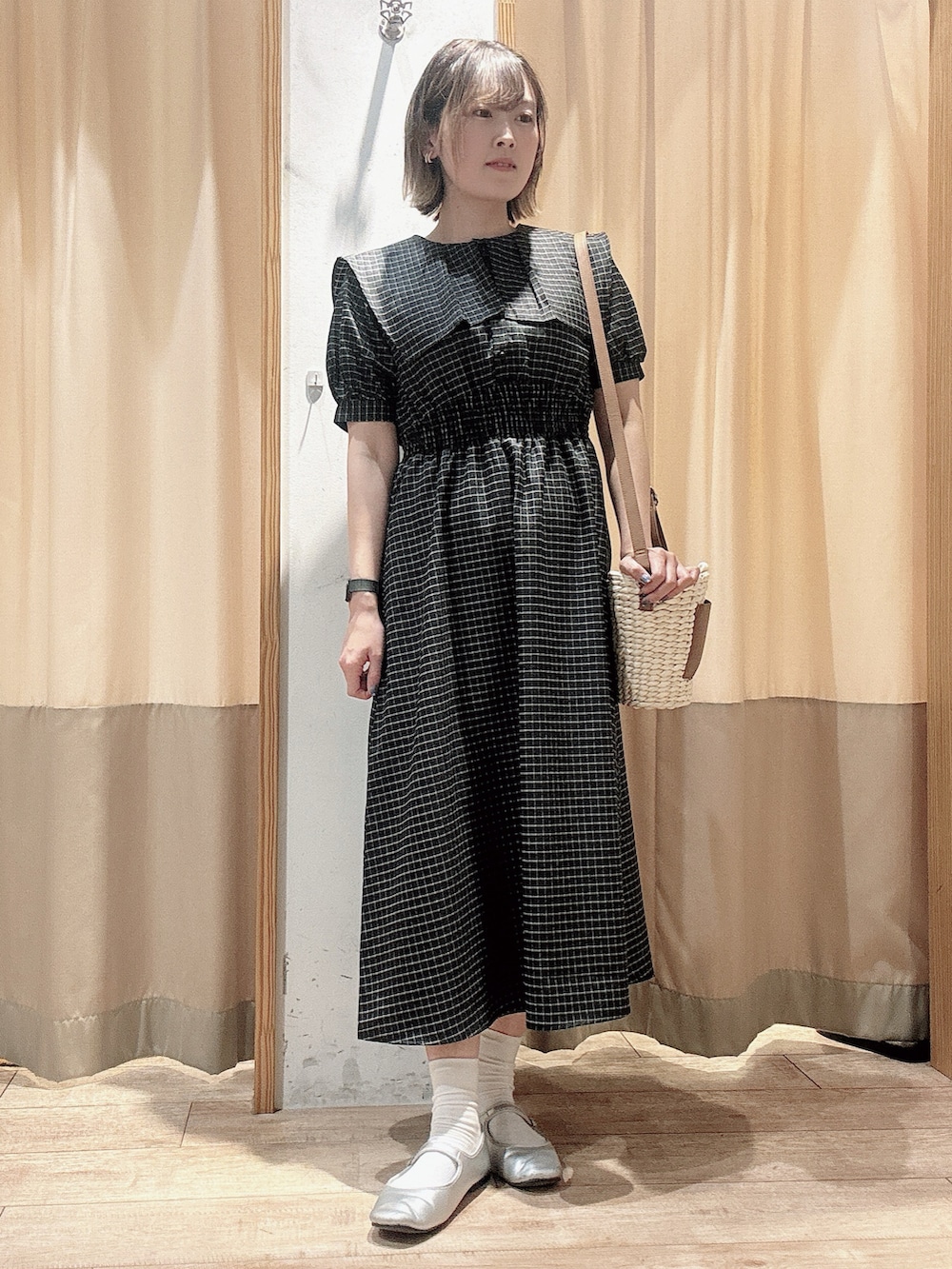 ブラック系のワンピース、ブラウン系のハンドバッグを着用したレディースの春コーディネートの2枚目の写真