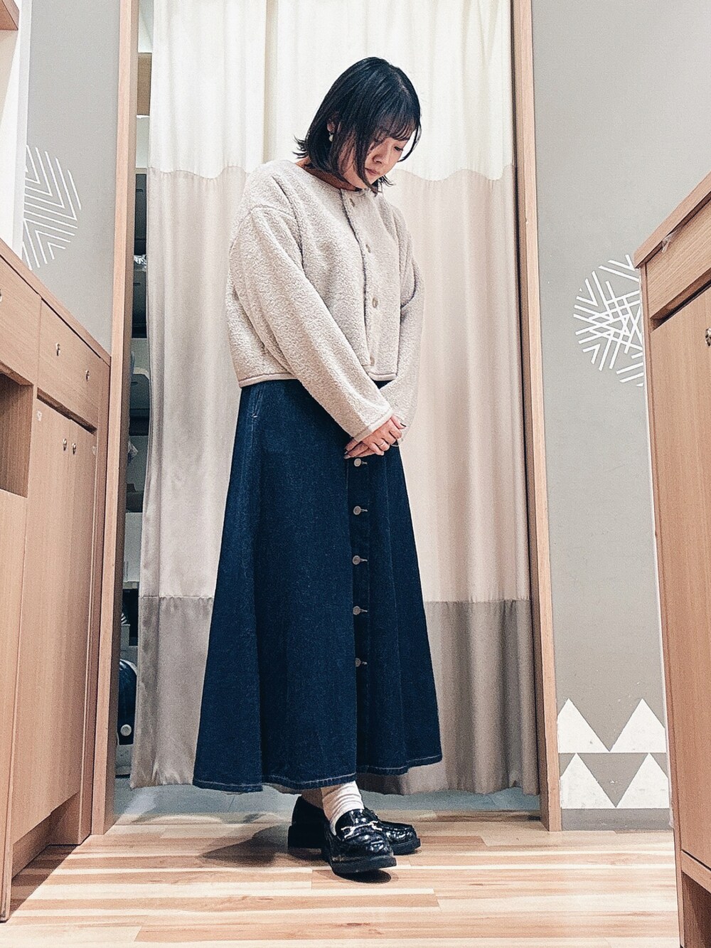 ベージュ系のブルゾン、ブルー系のスカート、オレンジ系のニット/セーターを着用したレディースの秋コーディネートの2枚目の写真