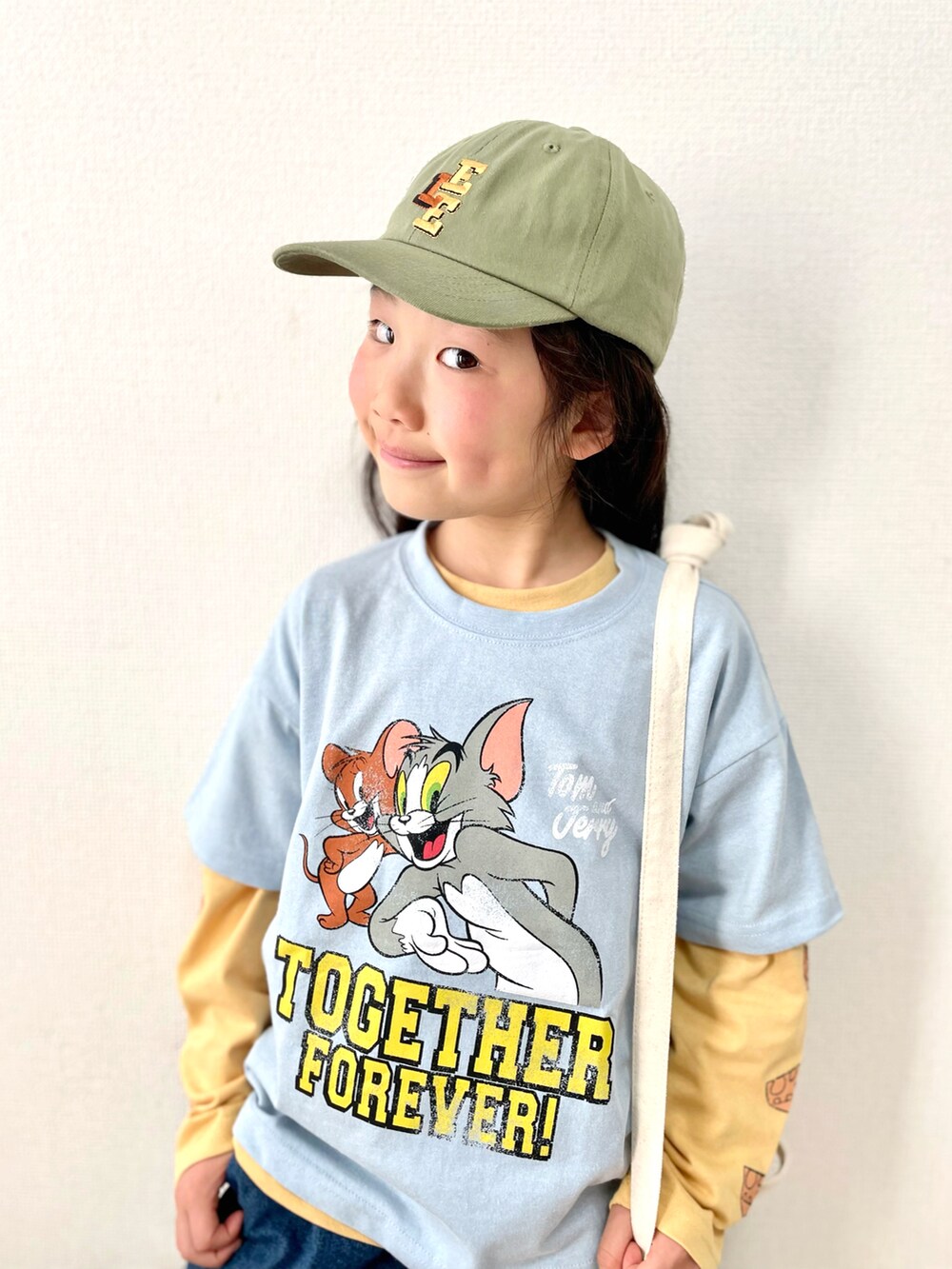 ブルー系のトップス、ブラウン系のショルダーバッグ、ブルー系のデニムパンツを着用したキッズの春コーディネートの2枚目の写真