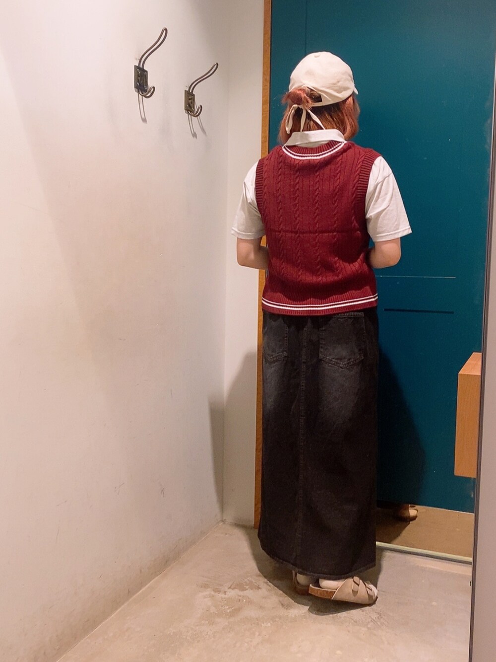 レッド系のベスト、グレー系のTシャツ/カットソー、ブラック系のスカートを着用したレディースの秋コーディネートの3枚目の写真