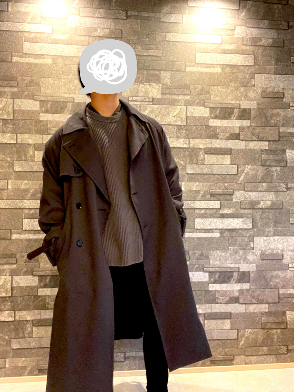 グレー系のトレンチコート、グレー系のニット/セーター、ブラック系のパンツを着用したメンズの冬コーディネートの2枚目の写真