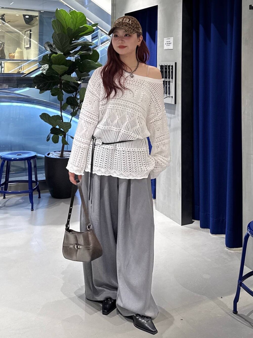 ブラウン系のハンドバッグ、ブラック系のサンダル、ホワイト系のニット/セーターを着用したレディースの春コーディネートの2枚目の写真