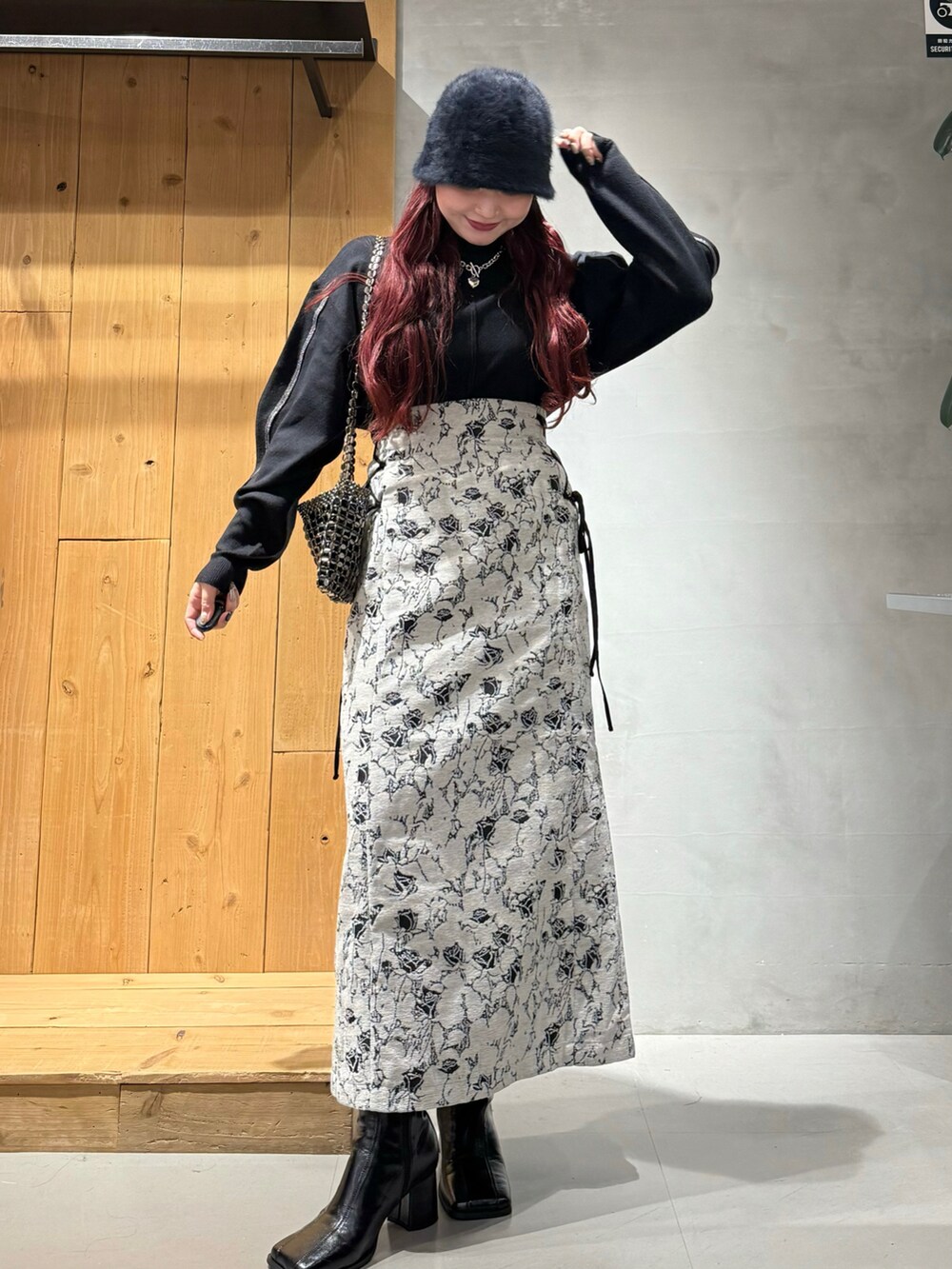 ブラック系のニット/セーター、ホワイト系のスカート、ブラック系のブーツを着用したレディースの秋コーディネートの2枚目の写真