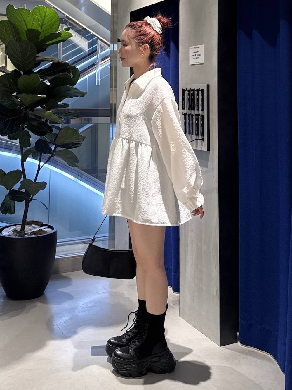 ブラック系のブーツ、ブラック系のハンドバッグ、ブラック系のスラックスを着用したレディースの春コーディネートの2枚目の写真