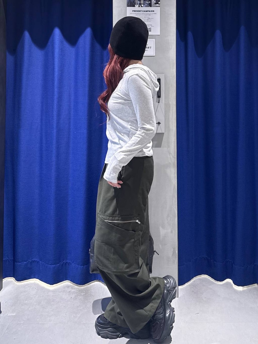 ブラック系のスニーカー、ブラック系のボストンバッグ、グリーン系のスラックスを着用したレディースの春コーディネートの2枚目の写真