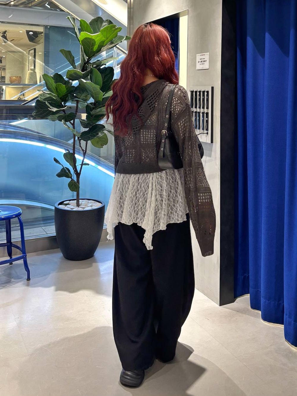 ブラック系のスニーカー、ブラック系のハンドバッグ、ホワイト系のチュニックを着用したレディースの春コーディネートの4枚目の写真