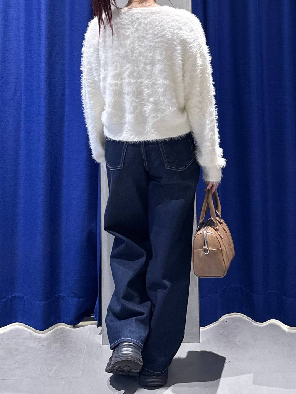 ブラック系のスニーカー、ブルー系のスラックス、ブラウン系のボストンバッグを着用したレディースの冬コーディネートの4枚目の写真