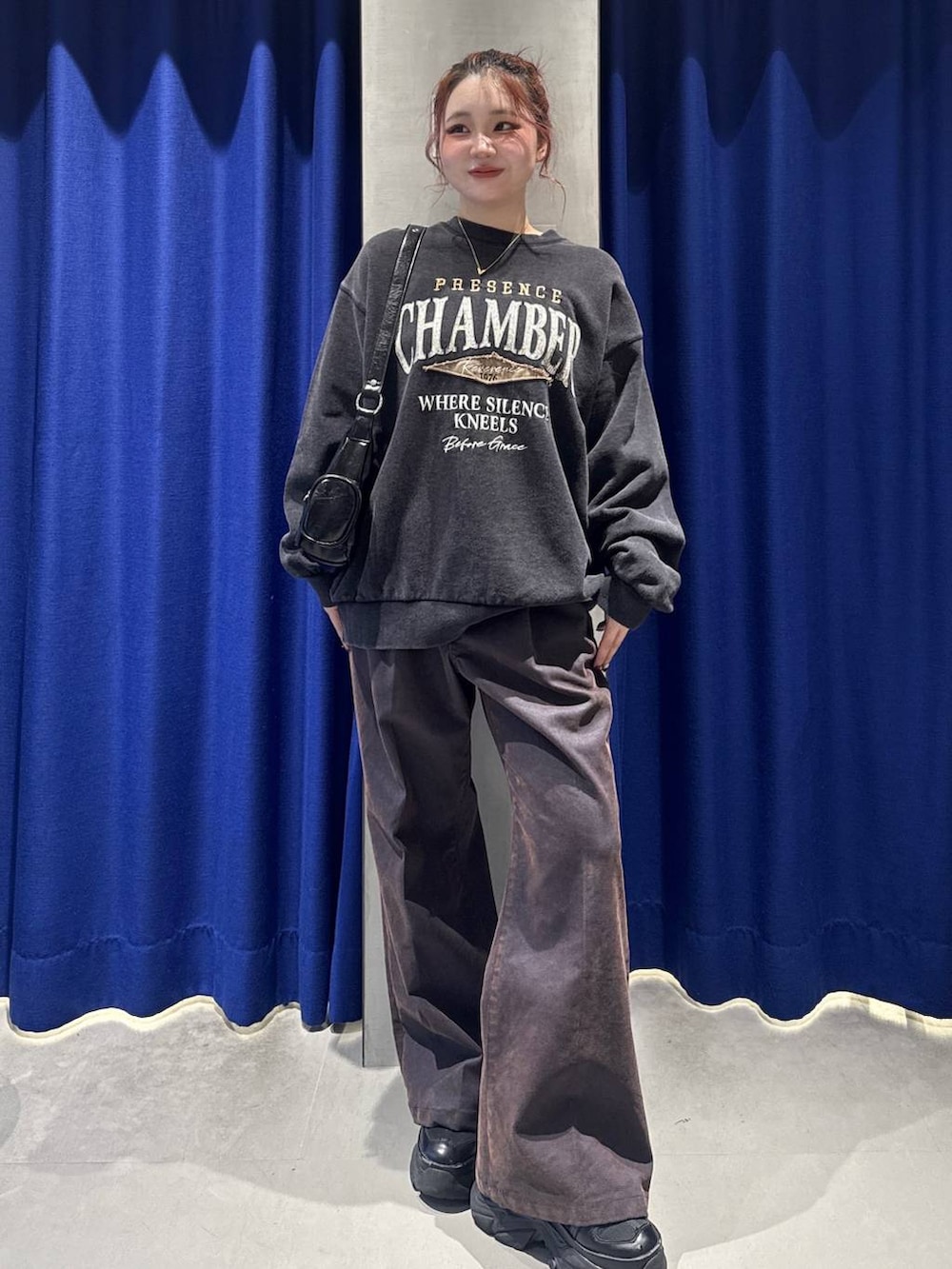 ブラック系のスニーカー、グレー系のスウェット、ブラック系のショルダーバッグを着用したレディースの冬コーディネートの2枚目の写真