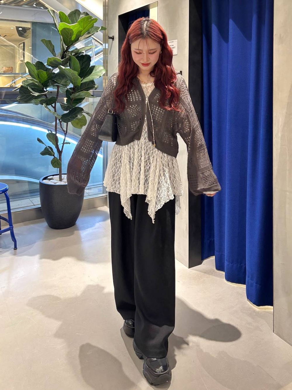 ブラック系のスニーカー、ブラック系のハンドバッグ、ホワイト系のチュニックを着用したレディースの春コーディネートの3枚目の写真