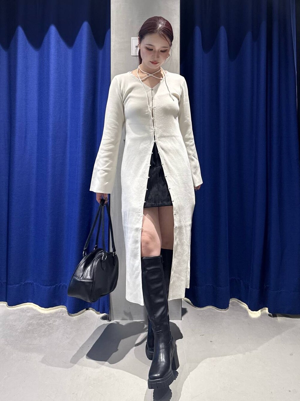 ホワイト系のワンピース、ブラック系のブーツ、ブラック系のボストンバッグを着用したレディースの秋コーディネートの2枚目の写真