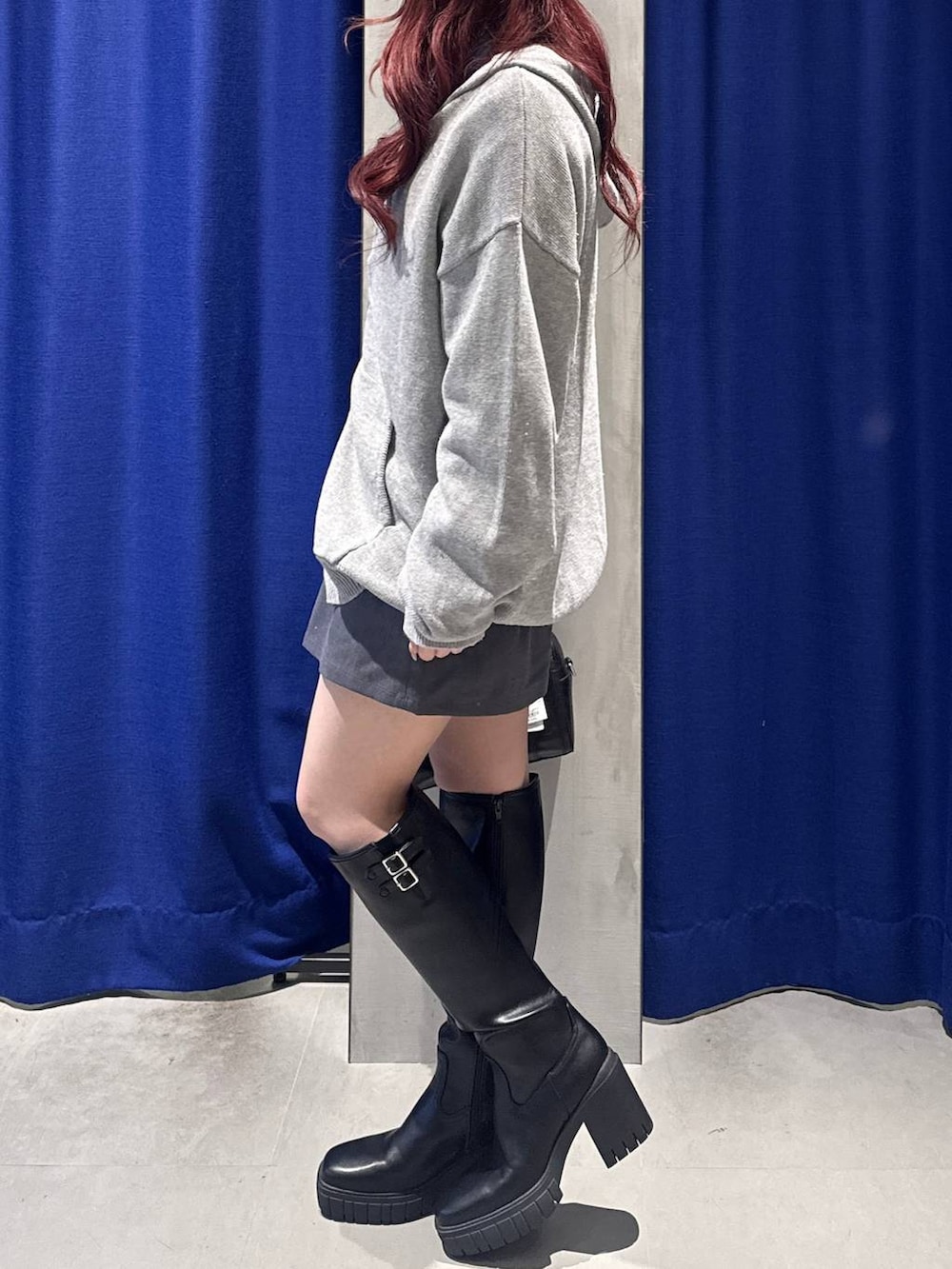 ブラック系のブーツ、グレー系のスカート、ブラック系のボストンバッグを着用したレディースの冬コーディネートの2枚目の写真