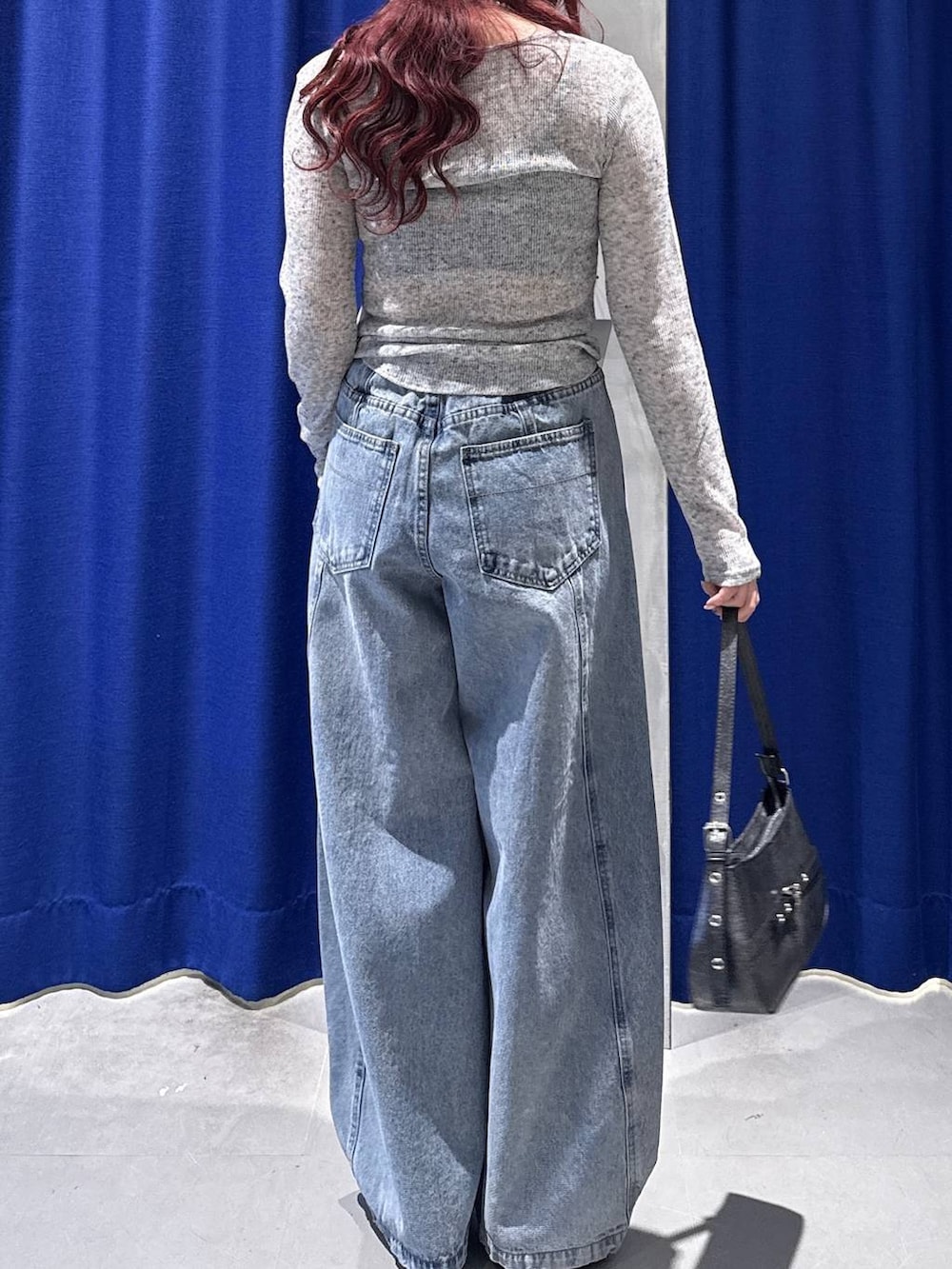 ブラック系のハンドバッグ、ブラック系のサンダル、ブルー系のデニムパンツを着用したレディースの春コーディネートの4枚目の写真