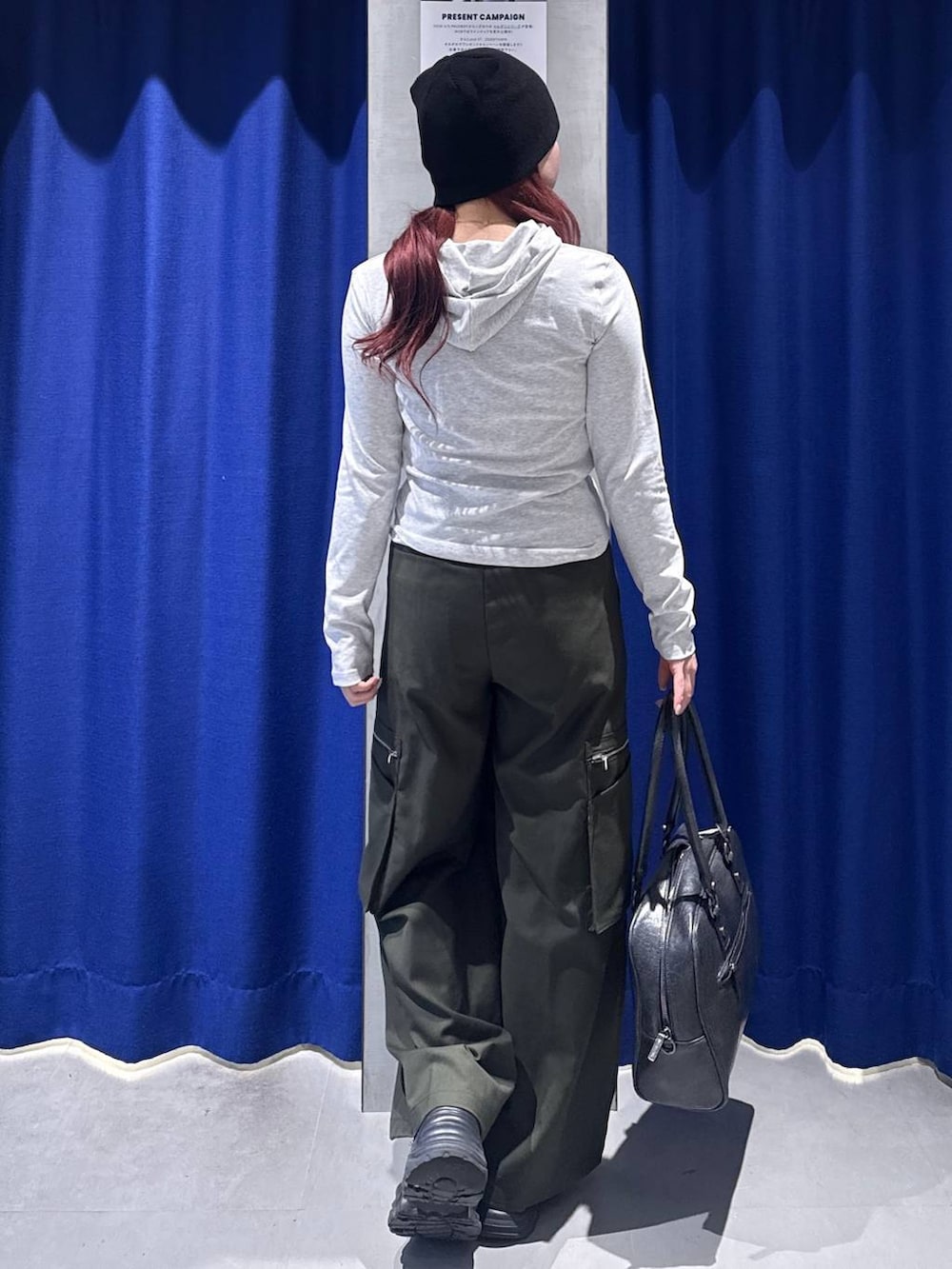 ブラック系のスニーカー、ブラック系のボストンバッグ、グリーン系のスラックスを着用したレディースの春コーディネートの3枚目の写真