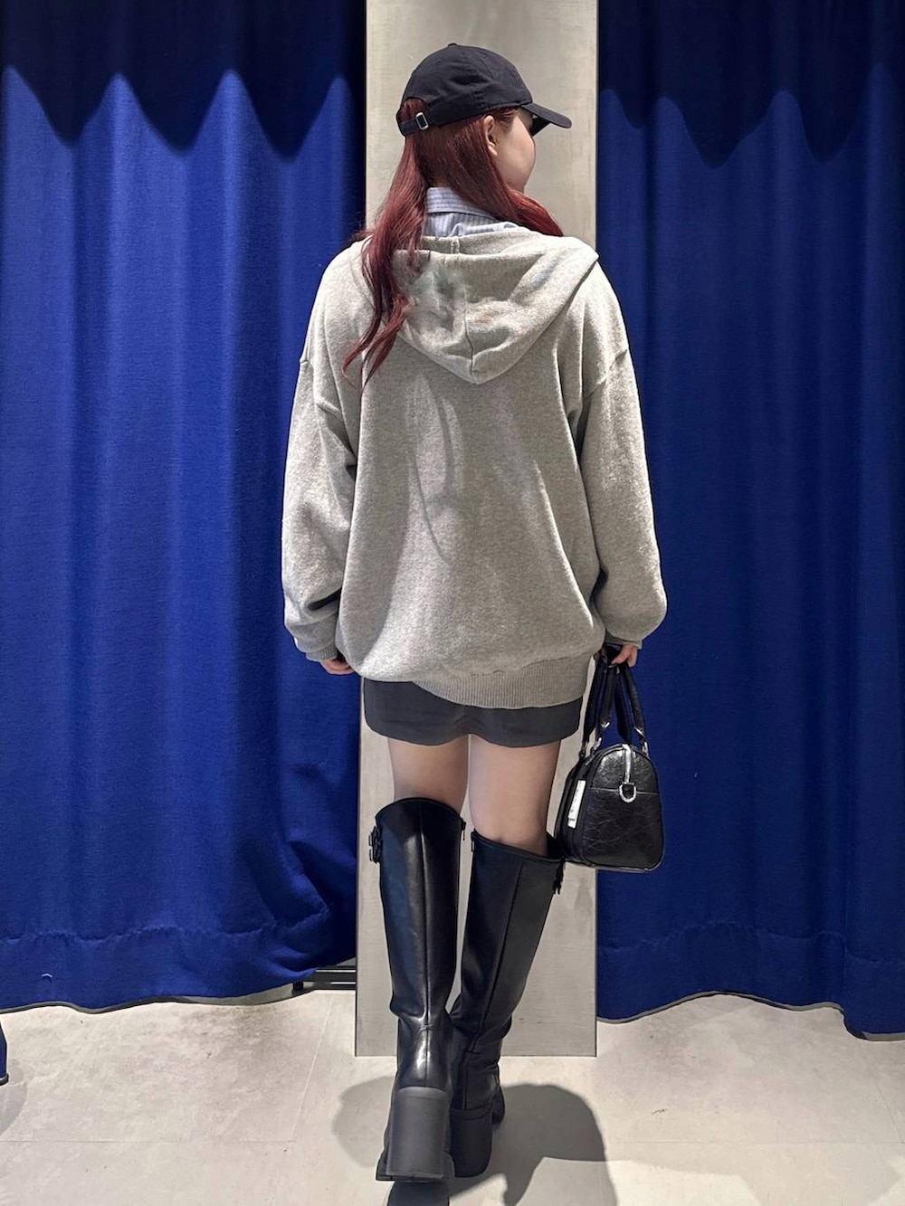 ブラック系のブーツ、グレー系のスカート、ブラック系のボストンバッグを着用したレディースの冬コーディネートの3枚目の写真