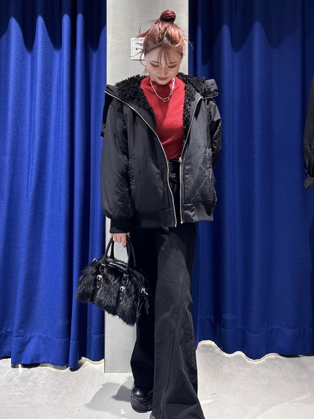 ブラック系のデニムパンツ、ブラック系のブルゾン、レッド系のニット/セーターを着用したレディースの秋コーディネートの2枚目の写真