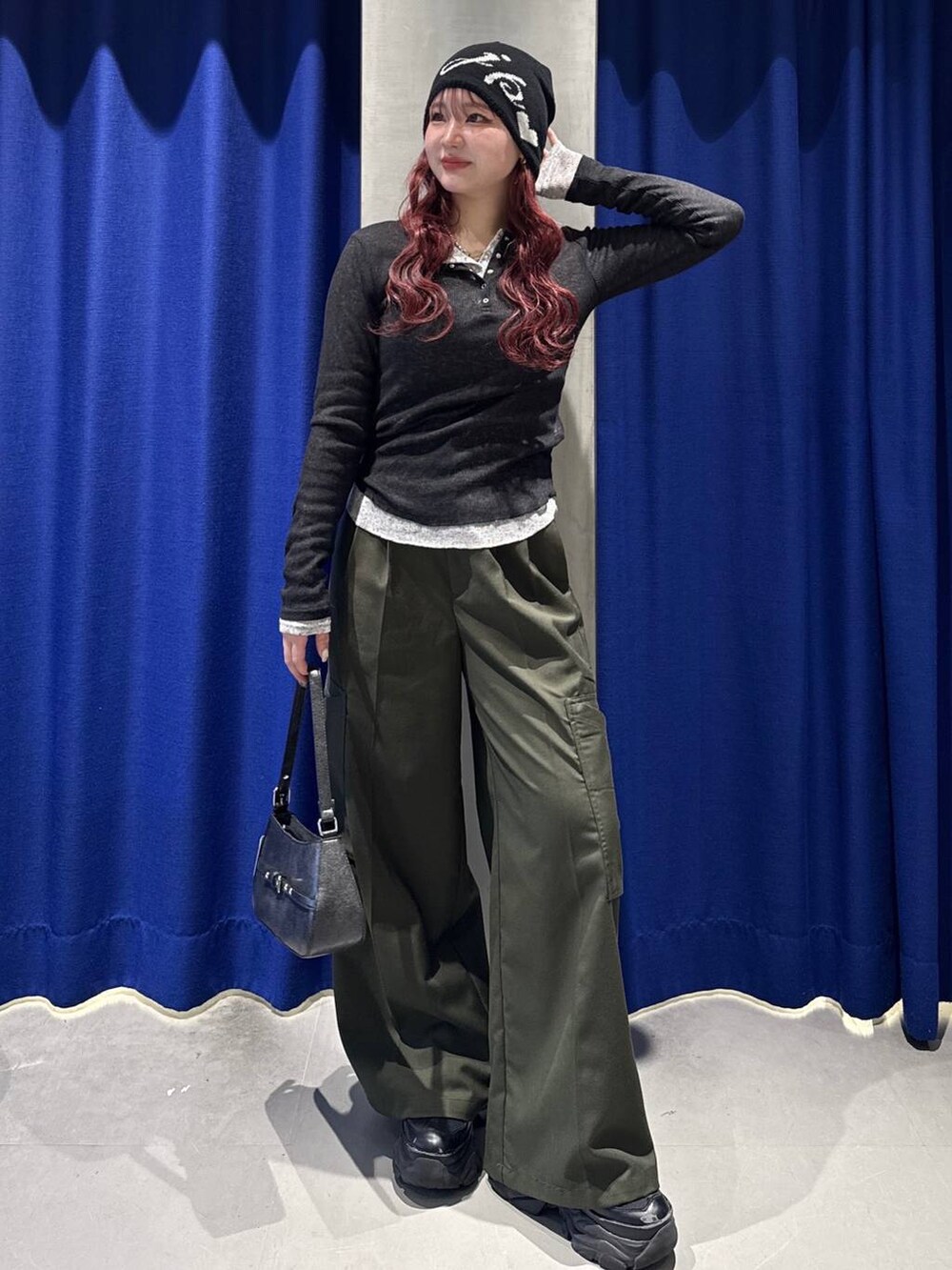 ブラック系のスニーカー、グリーン系のスラックス、ブラック系のハンドバッグを着用したレディースの春コーディネートの2枚目の写真