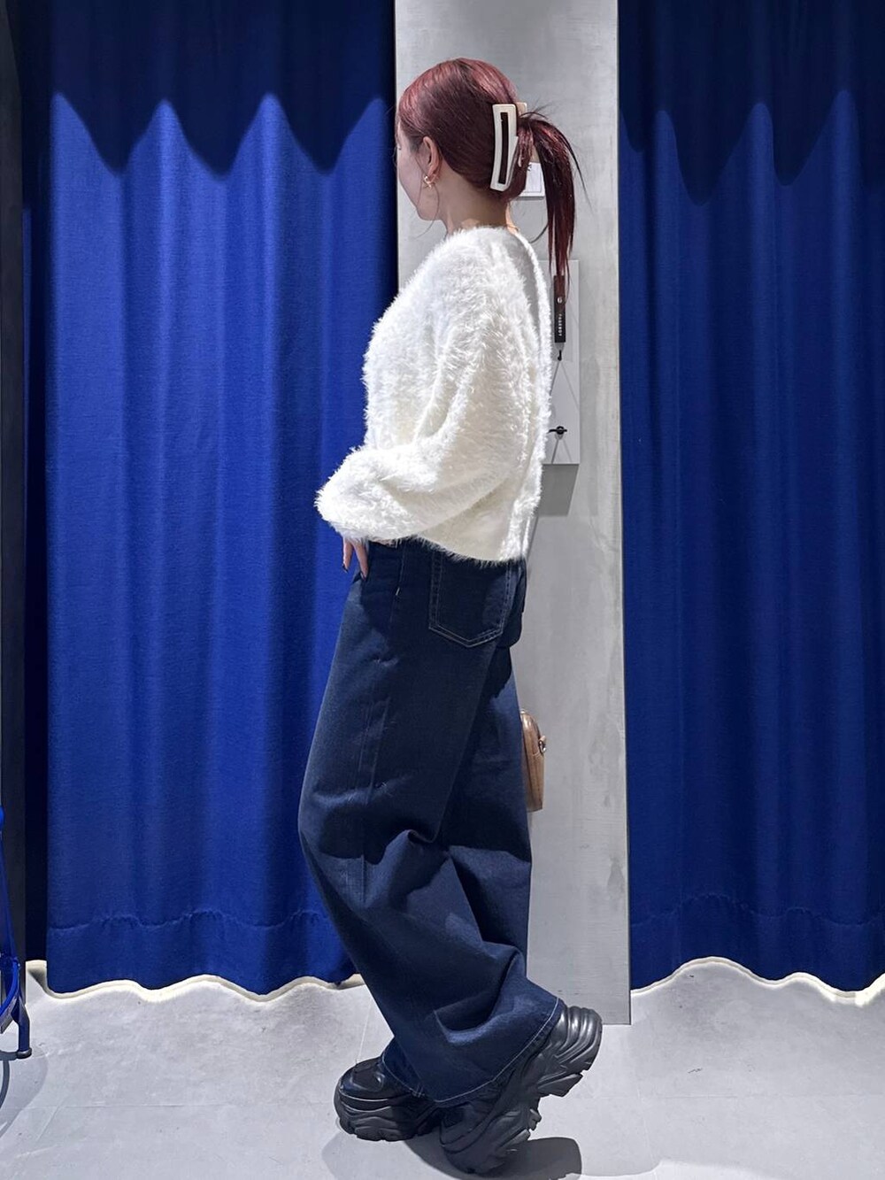 ブラック系のスニーカー、ブルー系のスラックス、ブラウン系のボストンバッグを着用したレディースの冬コーディネートの3枚目の写真