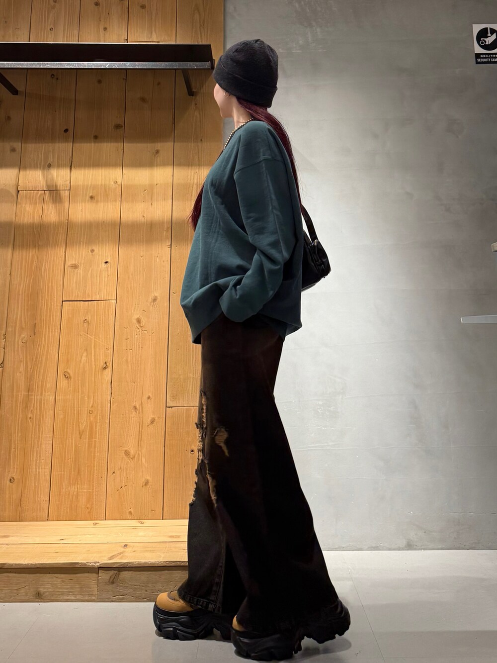 グリーン系のスウェット、ブラック系のデニムパンツ、ブラウン系のブーツを着用したレディースの冬コーディネートの3枚目の写真