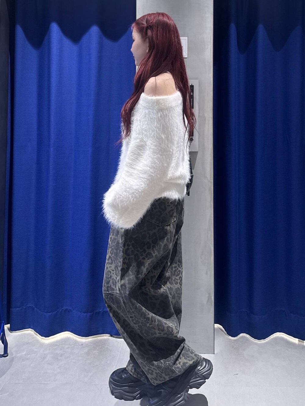 ブラック系のスニーカー、ホワイト系のニット/セーター、ブラック系のショルダーバッグを着用したレディースの冬コーディネートの2枚目の写真