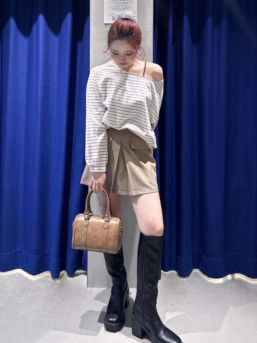 ブラック系のブーツ、ブラウン系のスカート、ブラウン系のボストンバッグを着用したレディースの冬コーディネートの2枚目の写真