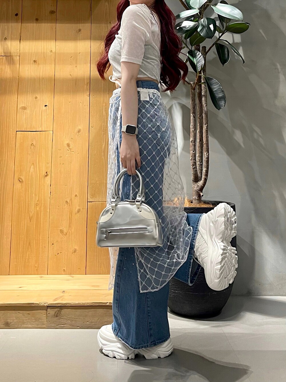 ブルー系のデニムパンツ、シルバー系のショルダーバッグ、ホワイト系のスニーカーを着用したレディースの夏コーディネートの4枚目の写真