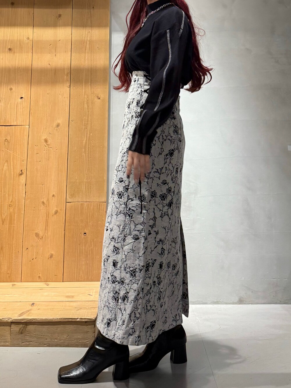 ブラック系のニット/セーター、ホワイト系のスカート、ブラック系のブーツを着用したレディースの秋コーディネートの4枚目の写真