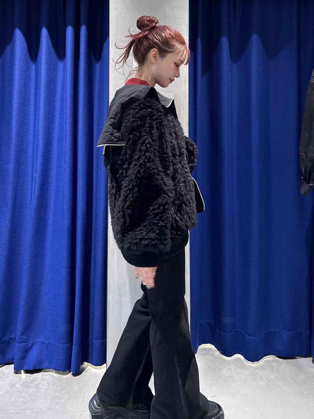 ブラック系のデニムパンツ、ブラック系のブルゾン、レッド系のニット/セーターを着用したレディースの秋コーディネートの3枚目の写真