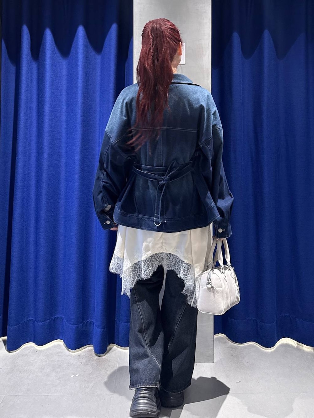 ブラック系のスニーカー、ブルー系のデニムパンツ、ホワイト系のボストンバッグを着用したレディースの冬コーディネートの3枚目の写真