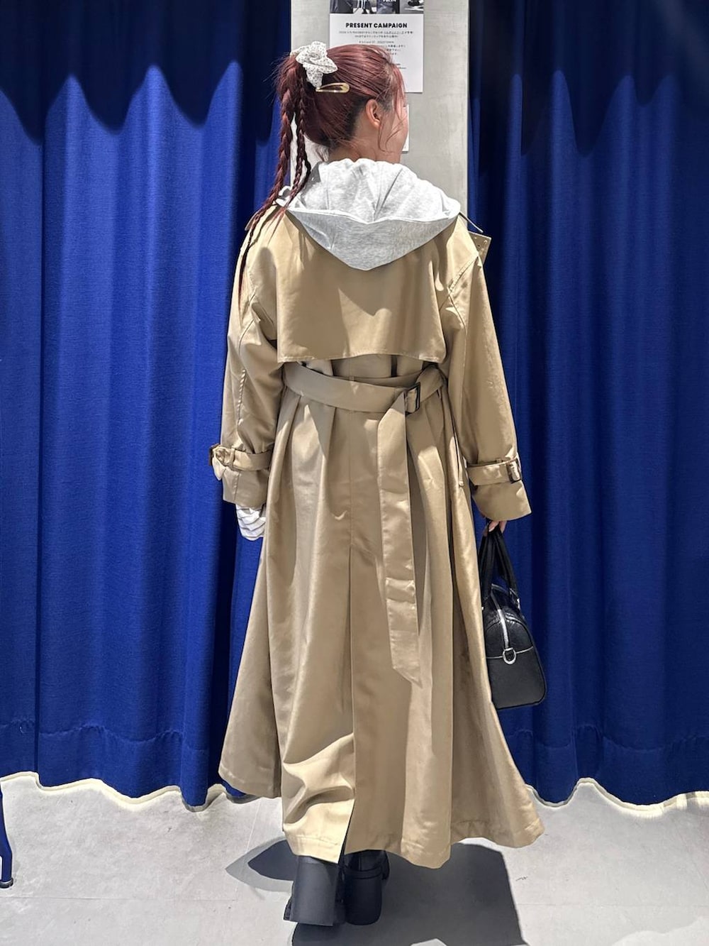 ブラック系のブーツ、ベージュ系のトレンチコート、ブラック系のボストンバッグを着用したレディースの冬コーディネートの3枚目の写真