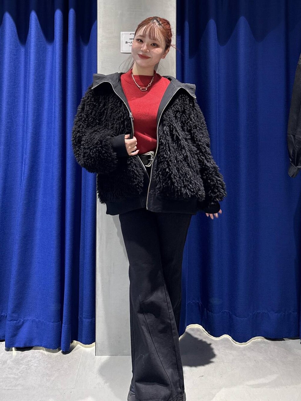 ブラック系のデニムパンツ、ブラック系のブルゾン、レッド系のニット/セーターを着用したレディースの秋コーディネートの4枚目の写真