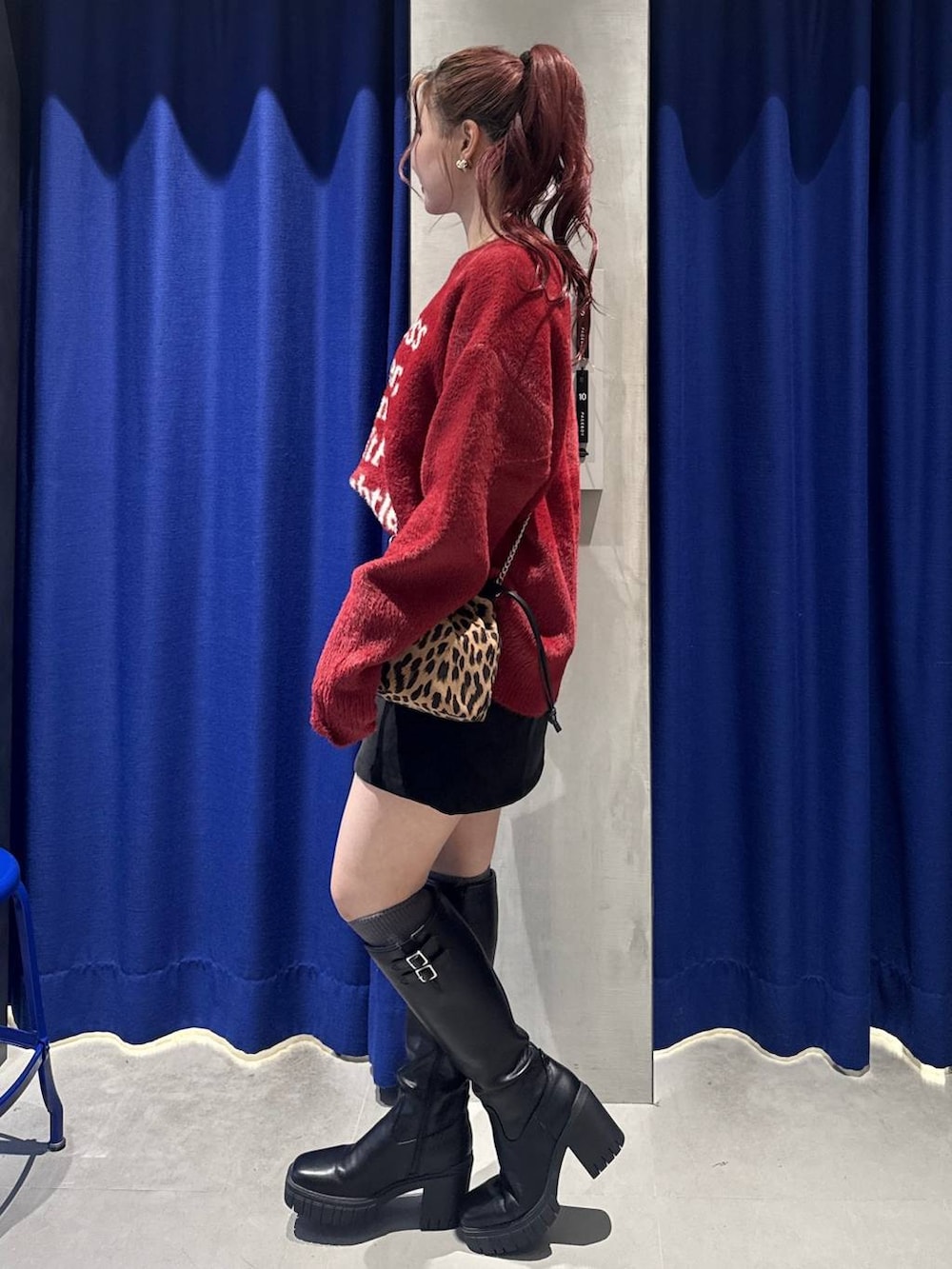 ブラック系のブーツ、ブラック系のスカート、レッド系のニット/セーターを着用したレディースの冬コーディネートの2枚目の写真