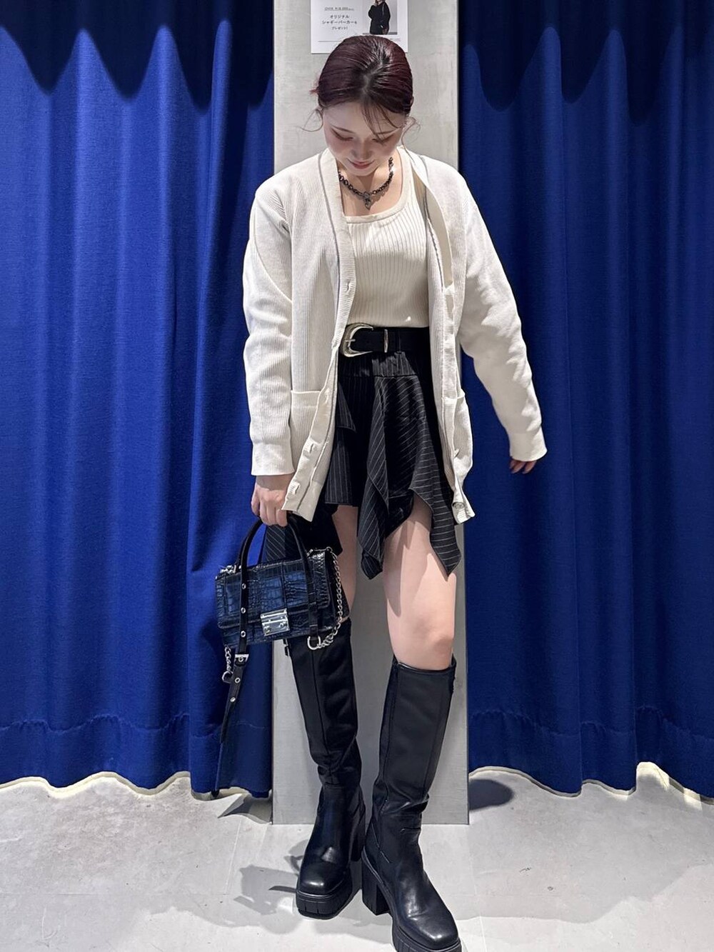 ホワイト系のタンクトップ、ブラック系のブーツ、ブラック系のハンドバッグを着用したレディースの秋コーディネートの2枚目の写真