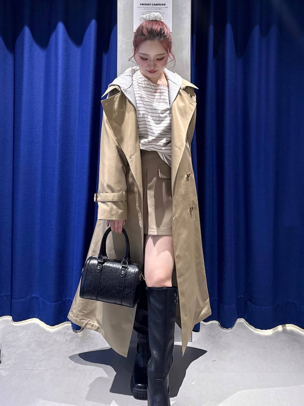 ブラック系のブーツ、ベージュ系のトレンチコート、ブラック系のボストンバッグを着用したレディースの冬コーディネートの2枚目の写真