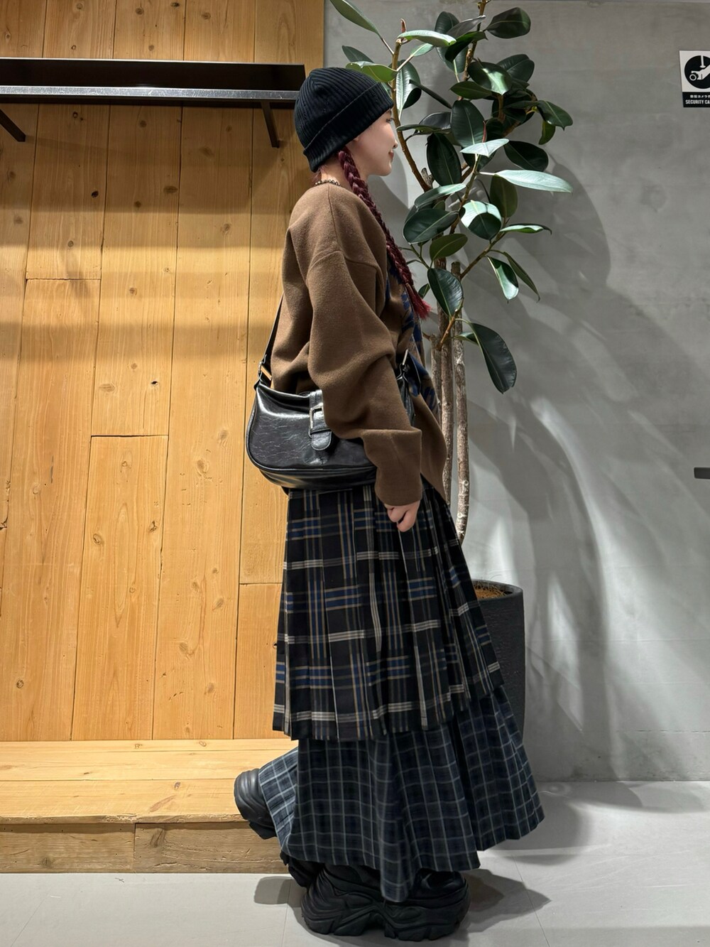 ブラック系のショルダーバッグ、ブラウン系のニット/セーター、ブルー系のスカートを着用したレディースの秋コーディネートの3枚目の写真