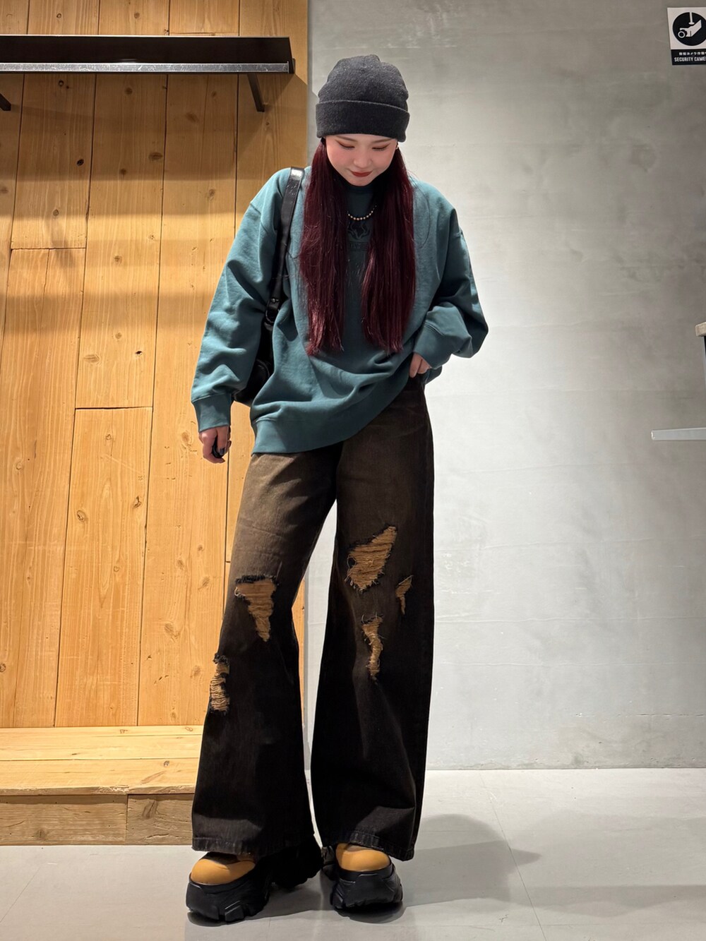 グリーン系のスウェット、ブラック系のデニムパンツ、ブラウン系のブーツを着用したレディースの冬コーディネートの2枚目の写真